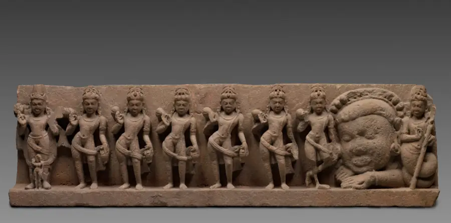 Ein Sturz aus Sandstein mit einer Reihe gemeißelter Figuren: die neun Himmelskörper, von der Sonne links bis zu einem körperlosen Kopf und einer Figur mit Schlangenschwanz rechts