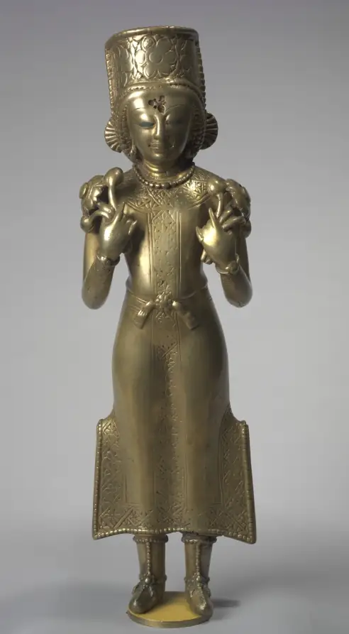 Eine stehende Messingfigur des Sonnengottes Surya in langer Tunika und Stiefeln, mit hoher Krone und erhobenen Händen