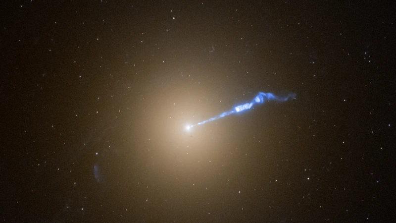 The giant galaxy M87 as a soft golden glow with a bright core and a blue jet shooting diagonally upward.