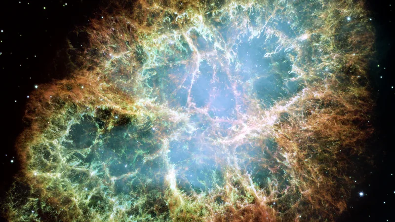 The Crab Nebula: a web of glowing green and orange gas filaments around a blue glow, against a black, starry background.