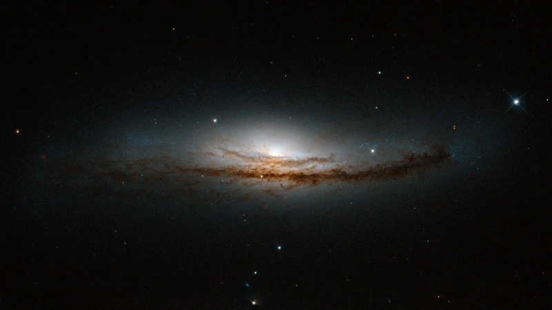 The galaxy NGC 5793 seen edge-on: a bright core with a dark dust lane running along it, against black.